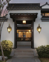 A pair of gold lanterns either side of a courtyard entrance door above stone steps