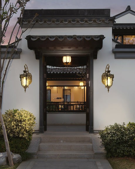 A pair of gold lanterns either side of a courtyard entrance door above stone steps
