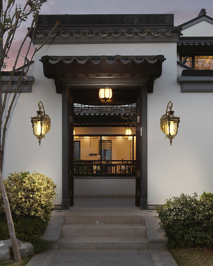 A pair of gold lanterns either side of a courtyard entrance door above stone steps