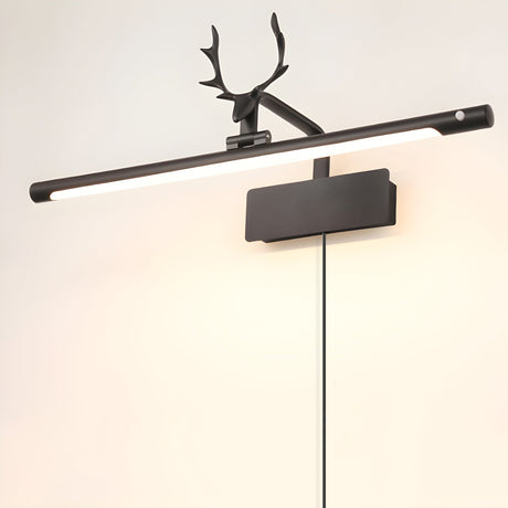 The black version lit on a warm wall, a dark stag head above the bright tube