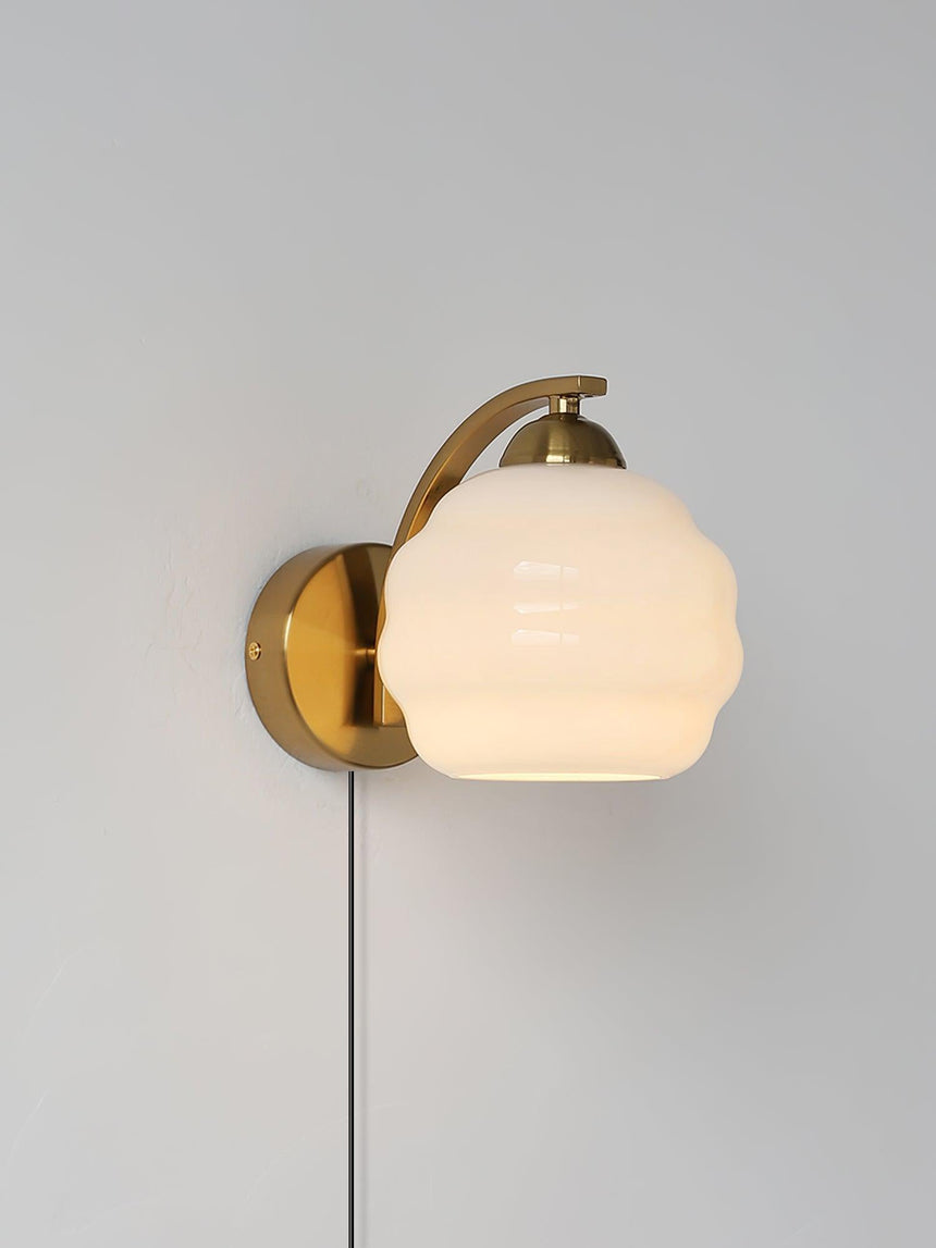 The gold sconce with a beige globe lit softly, the cord hanging straight