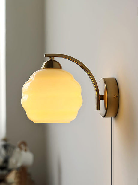 The gold plug-in sconce lit, its globe glowing warm and the cord below