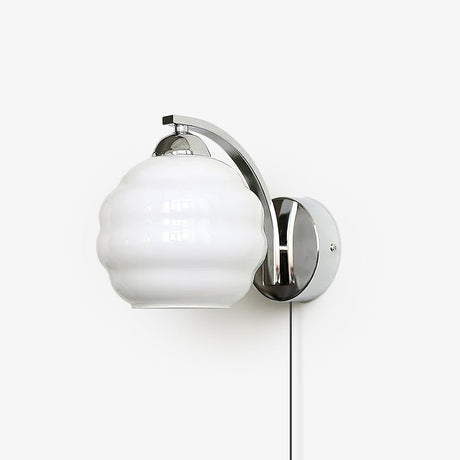 Plug-in wall sconce with a curved arm and a white ribbed glass globe, cord hanging