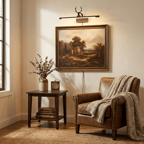 Gold bar lit above a framed landscape over a side table beside a leather armchair