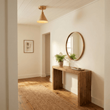 Cone ceiling light in a hallway above a wood console with a round mirror