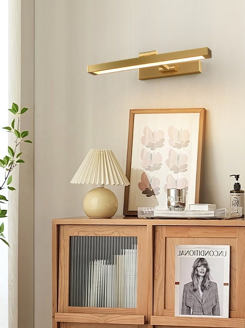 Gold bar lit above a glass fronted cabinet holding books and a print