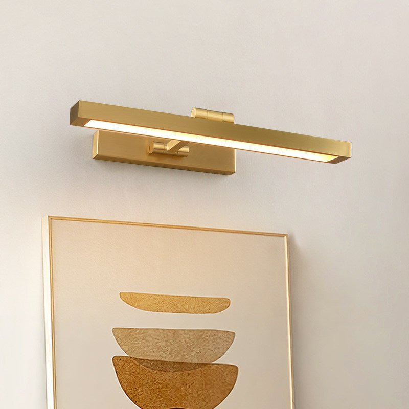 Gold bar lit above a framed abstract print on a warm painted wall