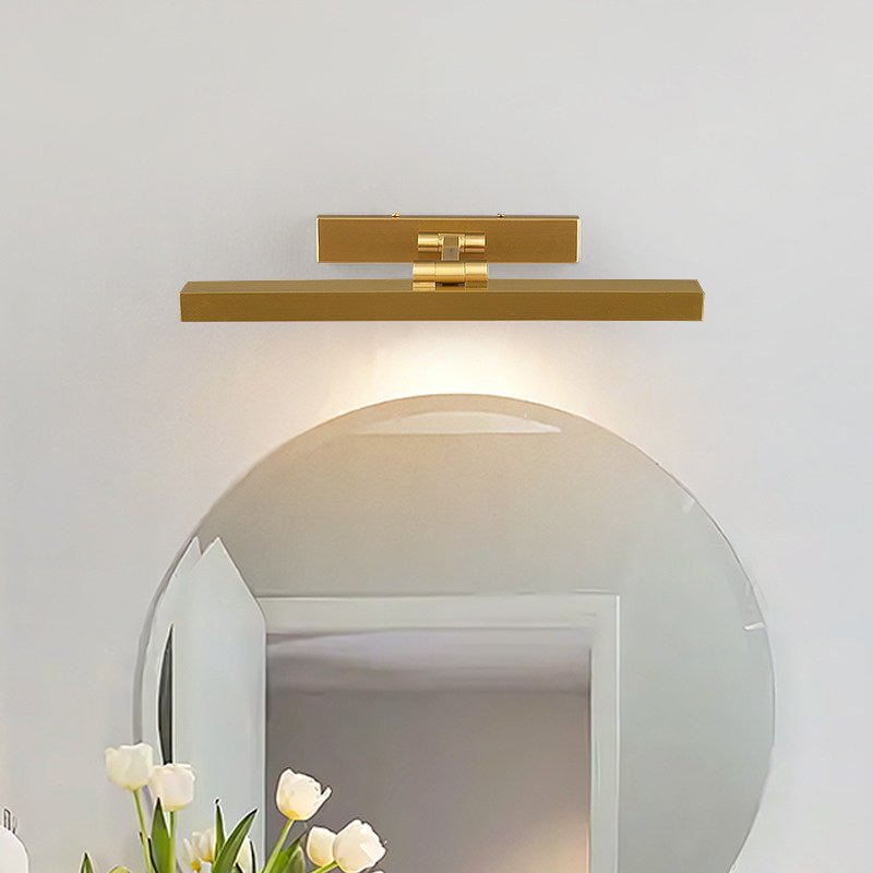Gold bar lit above a round mirror over a basin with white tulips