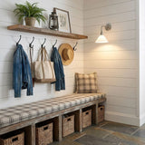 The sconce lit on a shiplap wall above an entry bench with hooks and baskets