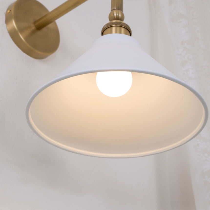 Inside the white cone shade, the bulb lit under the brass socket