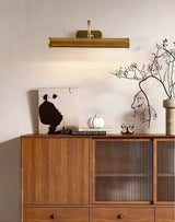 Copper tube lit over a framed line drawing propped on a reeded glass cabinet
