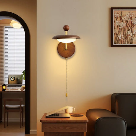 Sconce lit beside an arched mirror above a dressing table and a chair