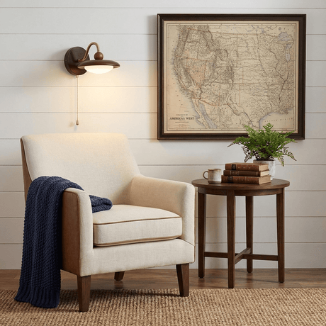 Sconce lit beside a framed map above a round side table and an armchair