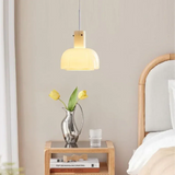 The beige glass shade lit beside a bed above a wooden nightstand
