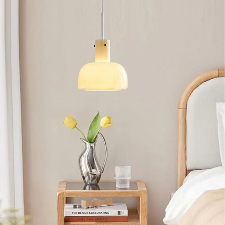 The beige glass shade lit beside a bed above a wooden nightstand