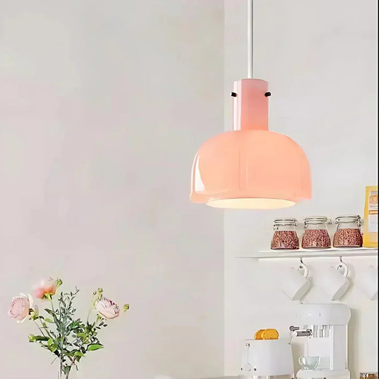 The pink glass shade lit above a shelf of jars and a vase of flowers