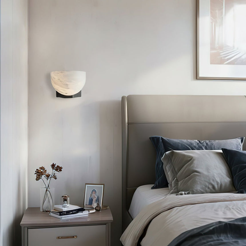 The lit bowl above a nightstand beside a bed with gray linens