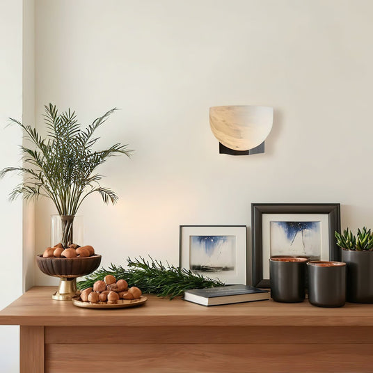 The lit bowl above a console with a potted palm, frames and canisters