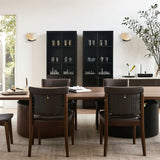 A pair lit on a dining room wall above a table with dark chairs