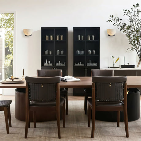 A pair lit on a dining room wall above a table with dark chairs