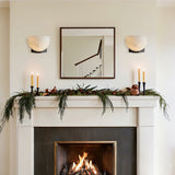 A pair lit above a lit fireplace with candles and garland on the mantel
