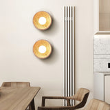 Two sconces lit on a dining wall above a wood table and curved chairs
