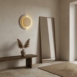 Sconce lit on a pale wall beside a tall leaning floor mirror