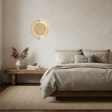 Sconce lit on a plaster bedroom wall above a low wood bench