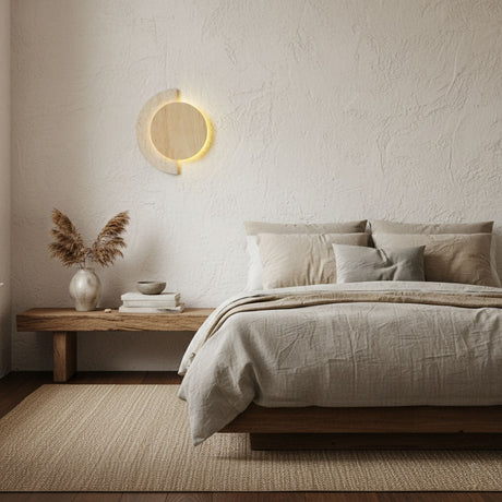 Sconce lit on a plaster bedroom wall above a low wood bench