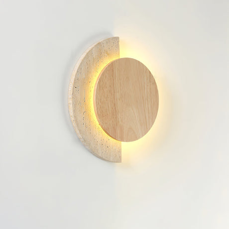 Travertine crescent lit behind a light wood disc, seen from an angle