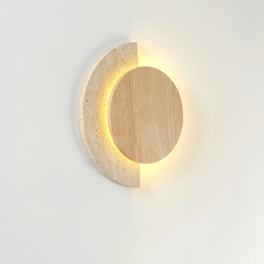 Travertine crescent lit behind a light wood disc, seen from an angle