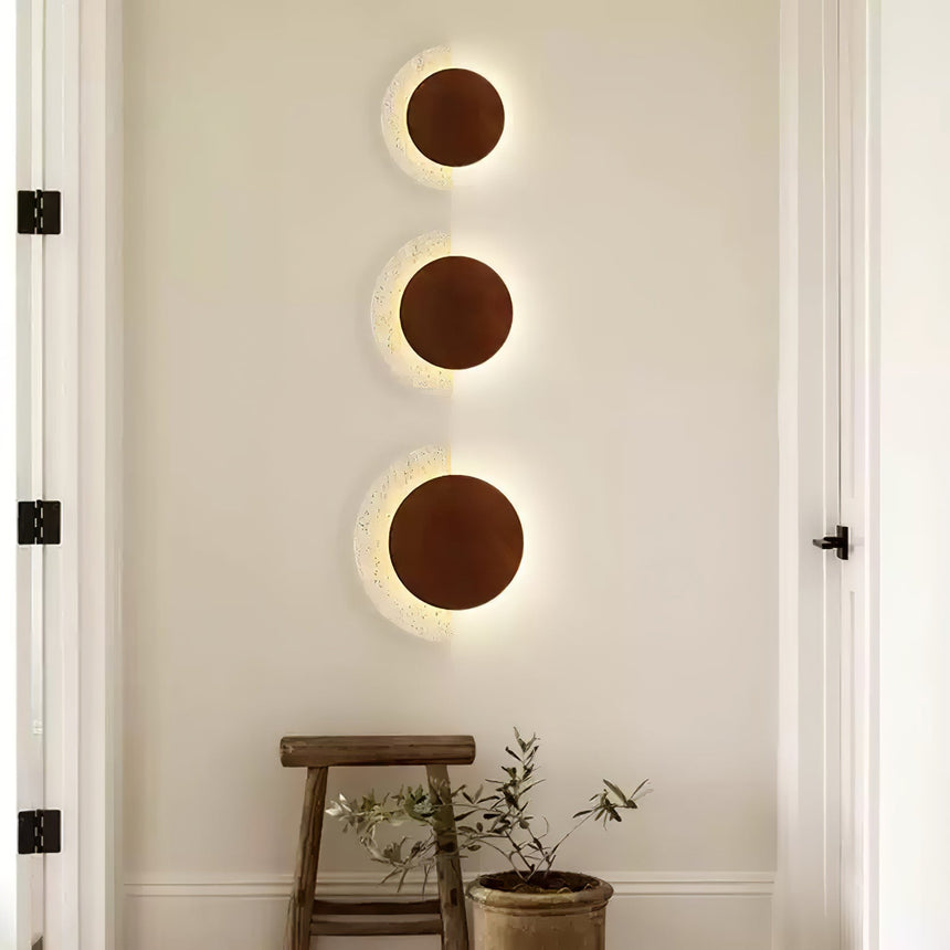 Three sconces of different sizes stacked in a column on one wall
