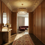 The lit fitting in a hallway above a runner rug, a console table and a round mirror