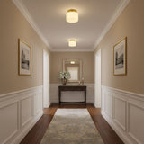 Brass and white glass ceiling lights in a corridor with wainscoting and a console