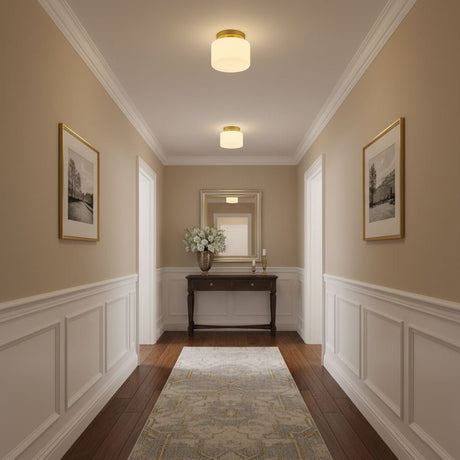 Brass and white glass ceiling lights in a corridor with wainscoting and a console