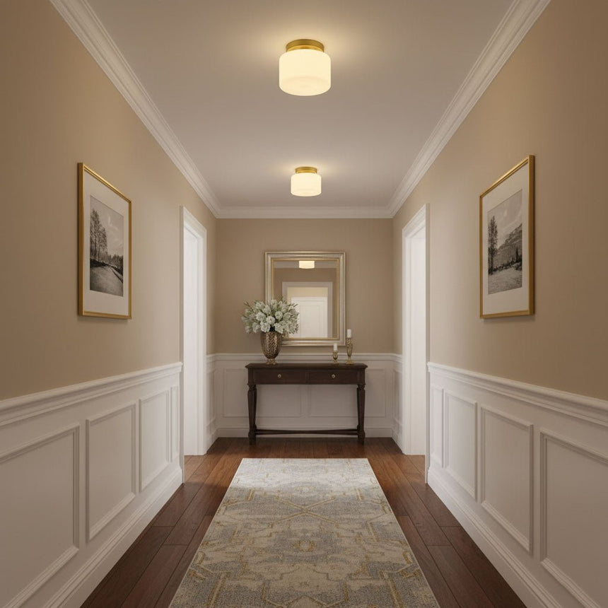 Brass and white glass ceiling lights in a corridor with wainscoting and a console