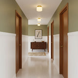 Brass and white glass ceiling lights in a green hallway with a wood sideboard