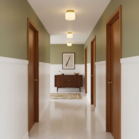 Brass and white glass ceiling lights in a green hallway with a wood sideboard