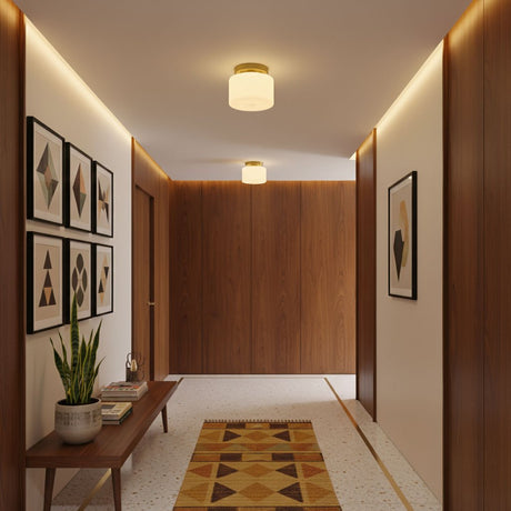 Brass and white glass ceiling lights in a wood paneled corridor with framed art