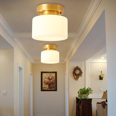 Two brass and white glass ceiling lights along a hallway with a round mirror