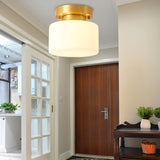 Brass and white glass ceiling light in a hallway with glazed doors and a console
