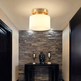 Brass and white glass ceiling light above a console against a stone wall