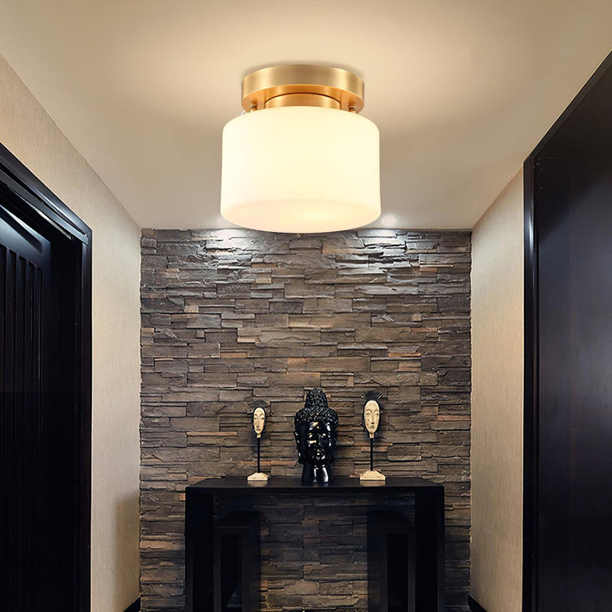 Brass and white glass ceiling light above a console against a stone wall