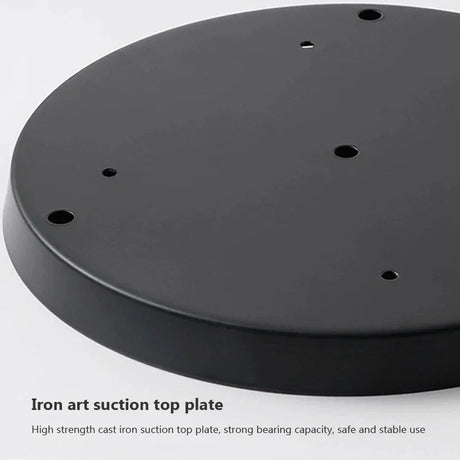 The black cast iron ceiling plate shown face down on a pale background