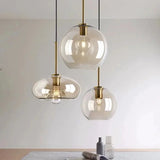 Three amber hand blown shades lit above a pale counter with a plant