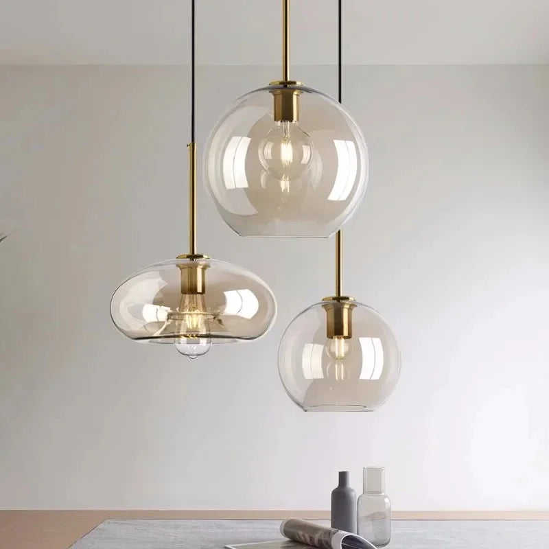Three amber hand blown shades lit above a pale counter with a plant