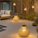 Lanterns hanging lit from a bare tree over a courtyard with a sofa
