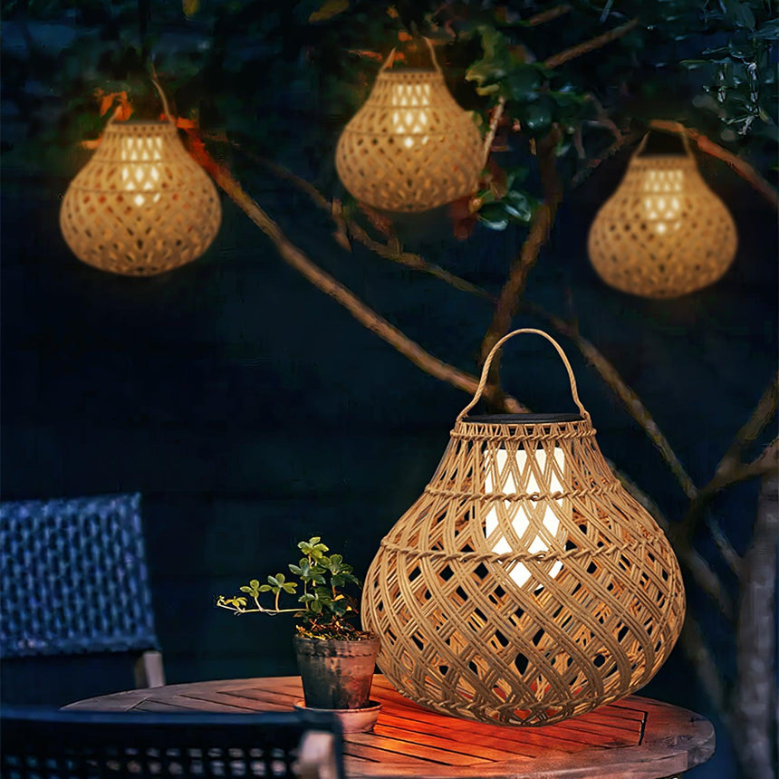 Four lanterns hanging lit from the branches of a tree above a terrace