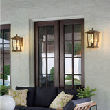 Two lanterns lit either side of french doors, a porch sofa with pillows below