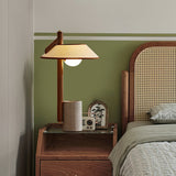 Cement base lamp lit on a nightstand beside a cane headboard